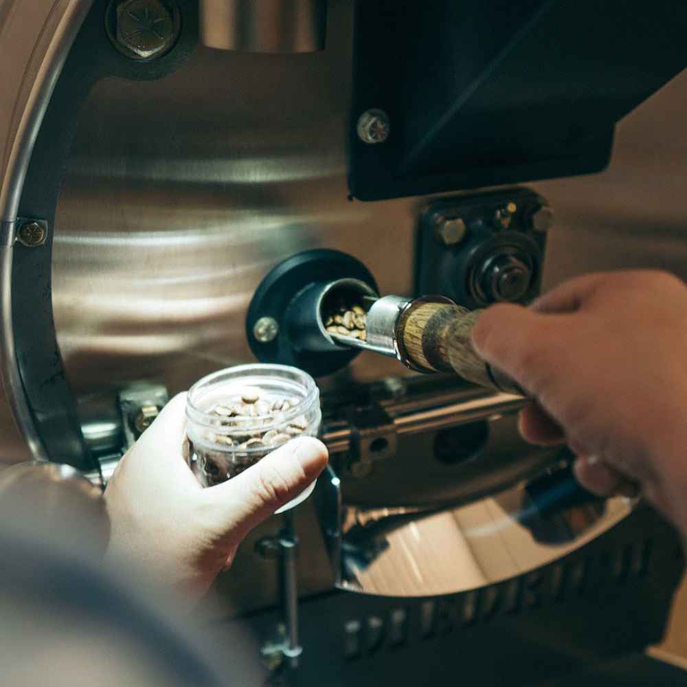 Man Puts Coffe In A Roasting Machine